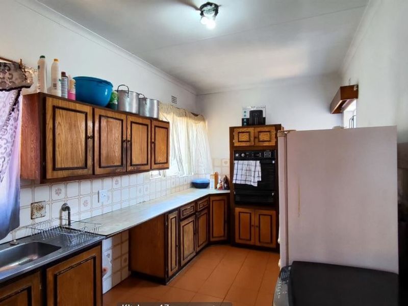 A dated kitchen featuring traditional wooden cabinetry, tiled backsplash, and built-in oven, offering a functional layout with potential for modern renovation.