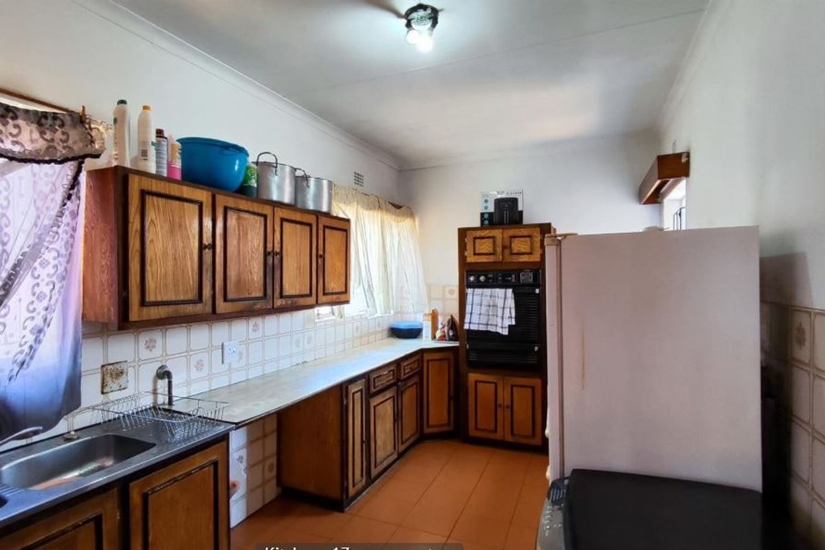 A dated kitchen featuring traditional wooden cabinetry, tiled backsplash, and built-in oven, offering a functional layout with potential for modern renovation.