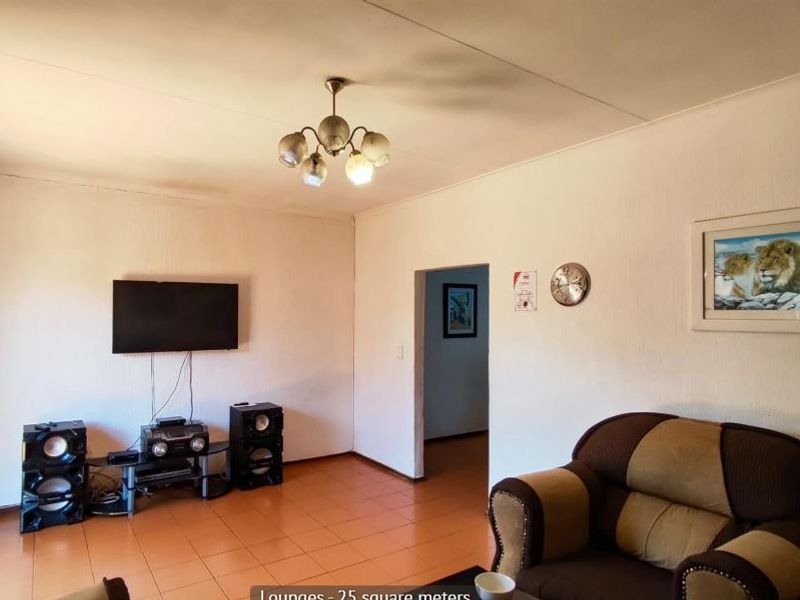A living room featuring tiled flooring and a central ceiling light fixture, showing signs of wear on the ceiling.