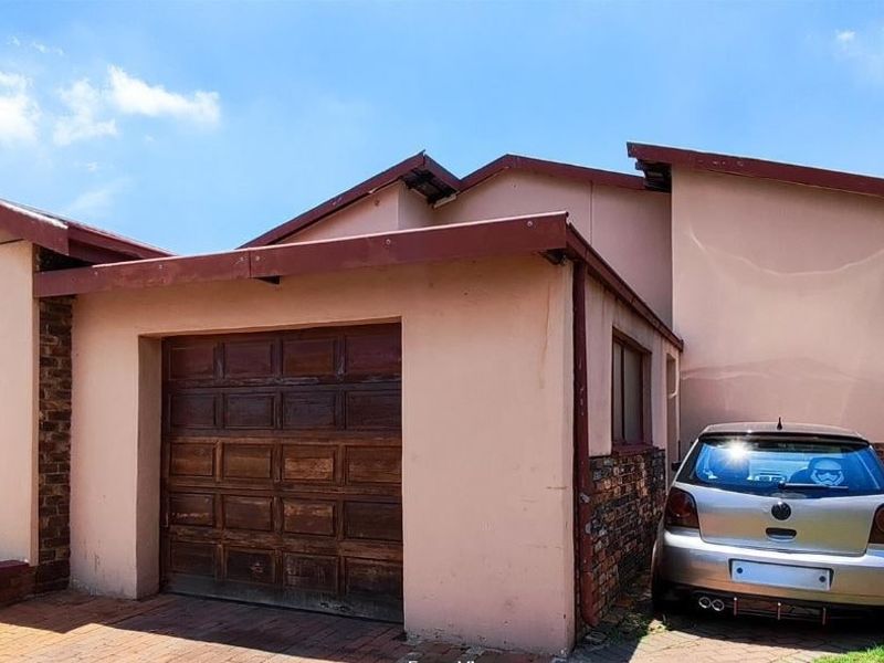 Front exterior view of the property featuring a double garage with a paved driveway and traditional tiled roof architecture.