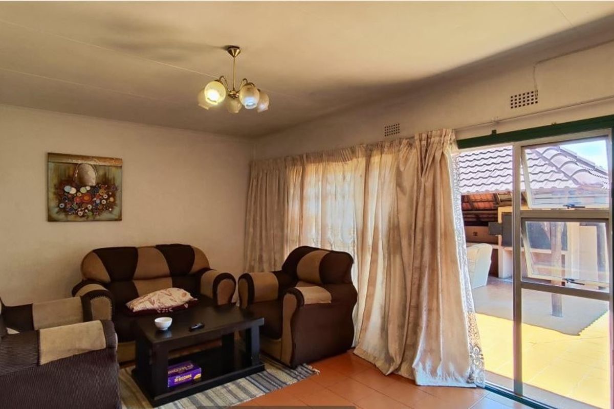 A living room featuring tiled flooring and a large sliding glass door providing access to an outdoor patio area.
