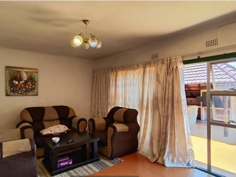 A living room featuring tiled flooring and a large sliding glass door providing access to an outdoor patio area.