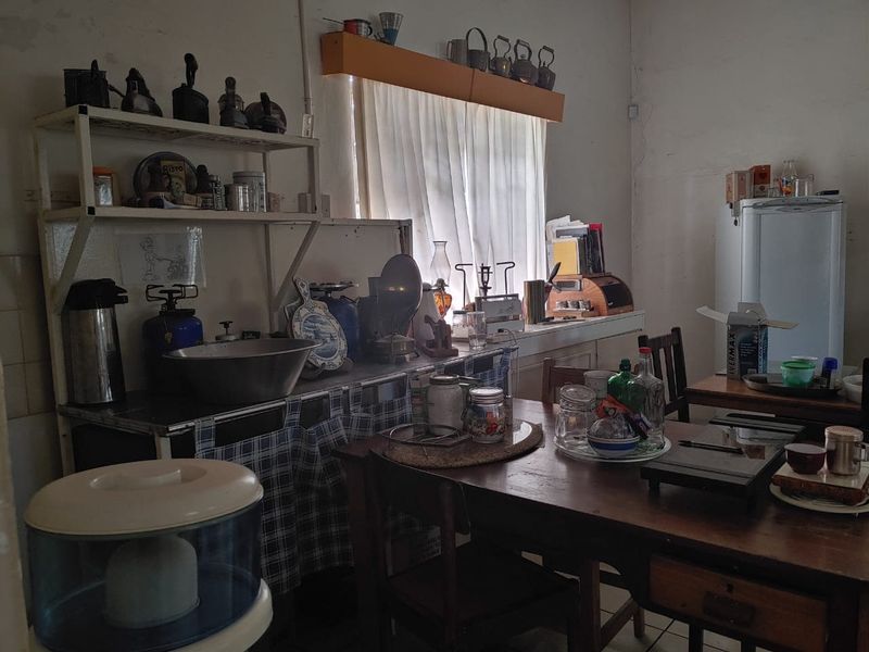 A dated kitchen area featuring built-in shelving and tiled flooring, currently showing signs of wear and requiring cosmetic updates to improve its overall condition.