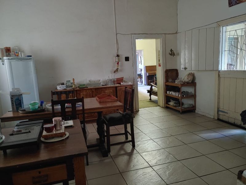 A living area featuring tiled flooring and direct access to adjacent rooms, showing signs of wear and requiring cosmetic updates.