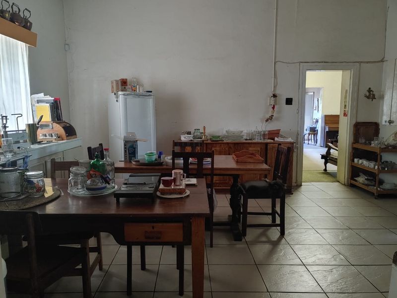 A dated kitchen area featuring tiled flooring and original cabinetry, requiring cosmetic updates and electrical maintenance to modernize the space.