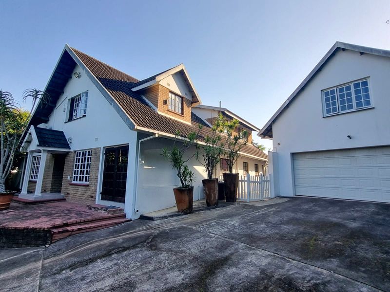 Front view of a multi-story house featuring a tiled roof, brick accents, and an attached double garage with a paved driveway.