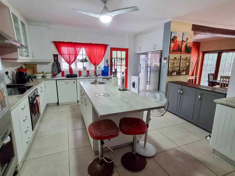 Spacious kitchen featuring a central island, built-in cabinetry, integrated appliances, and tiled flooring, offering a functional layout with potential for modern updates.