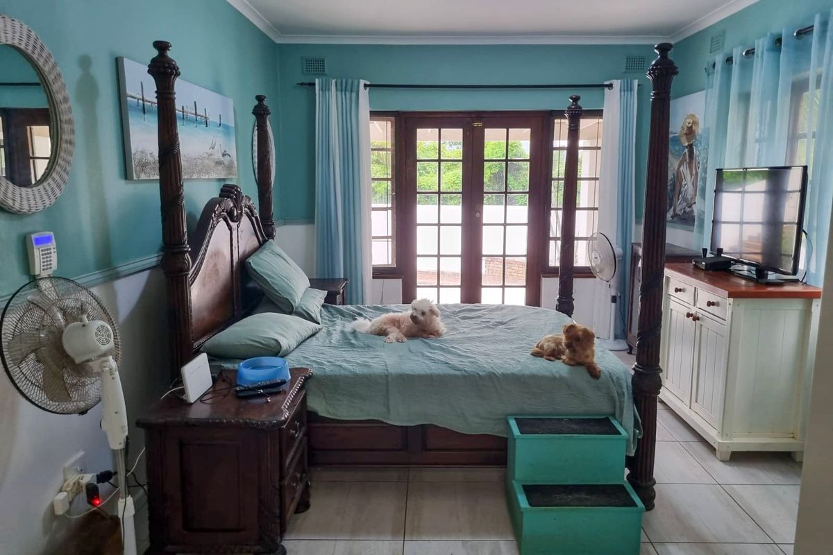 A bedroom featuring tiled flooring and wooden french doors leading to an outdoor area, providing natural light and access to the exterior.