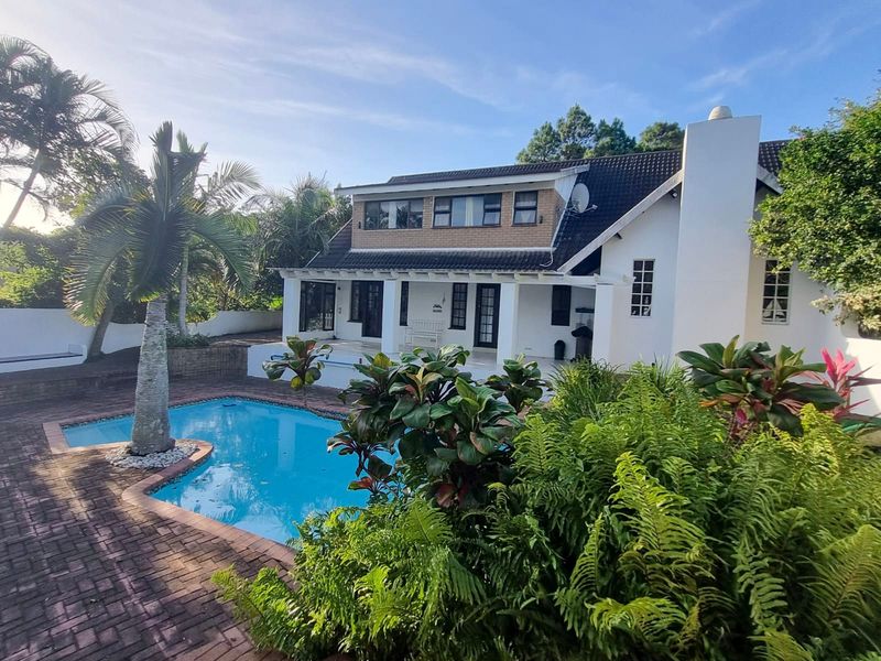 Rear view of the property featuring a swimming pool, brick paved patio area, and a well-maintained two-story building facade.