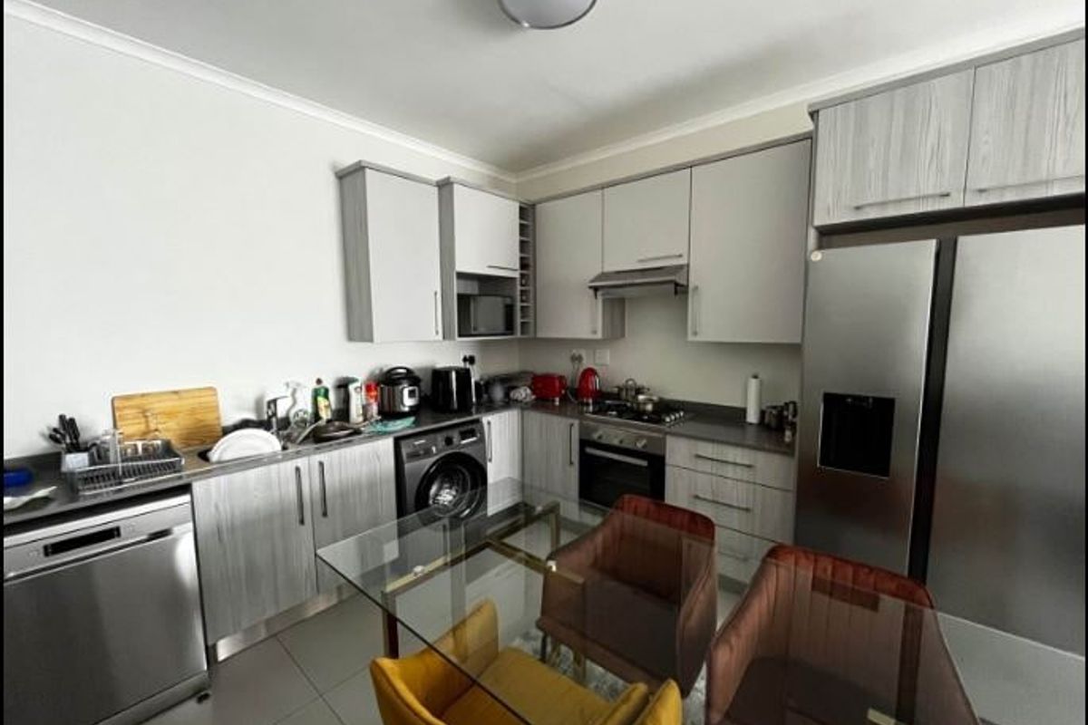Modern kitchen featuring light wood-grain cabinetry, stainless steel appliances, built-in oven with gas hob, and tiled flooring in an open-plan layout.