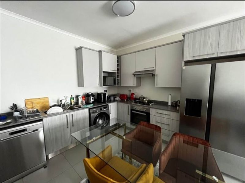Modern kitchen featuring light wood-grain cabinetry, stainless steel appliances, built-in oven with gas hob, and tiled flooring in an open-plan layout.