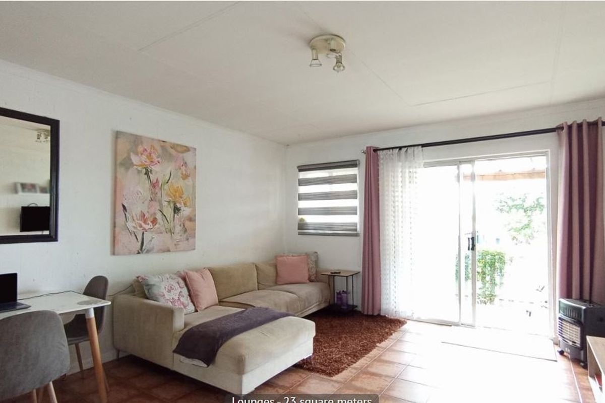 A bright living room featuring tiled flooring and a large sliding glass door providing access to the outdoor area.
