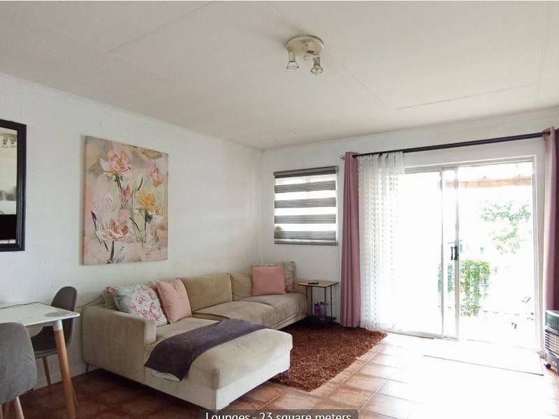 A bright living room featuring tiled flooring and a large sliding glass door providing access to the outdoor area.