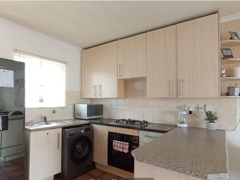 Functional kitchen featuring light wood-finish cabinetry, stone-look countertops, a built-in oven with gas hob, and a convenient breakfast bar area.