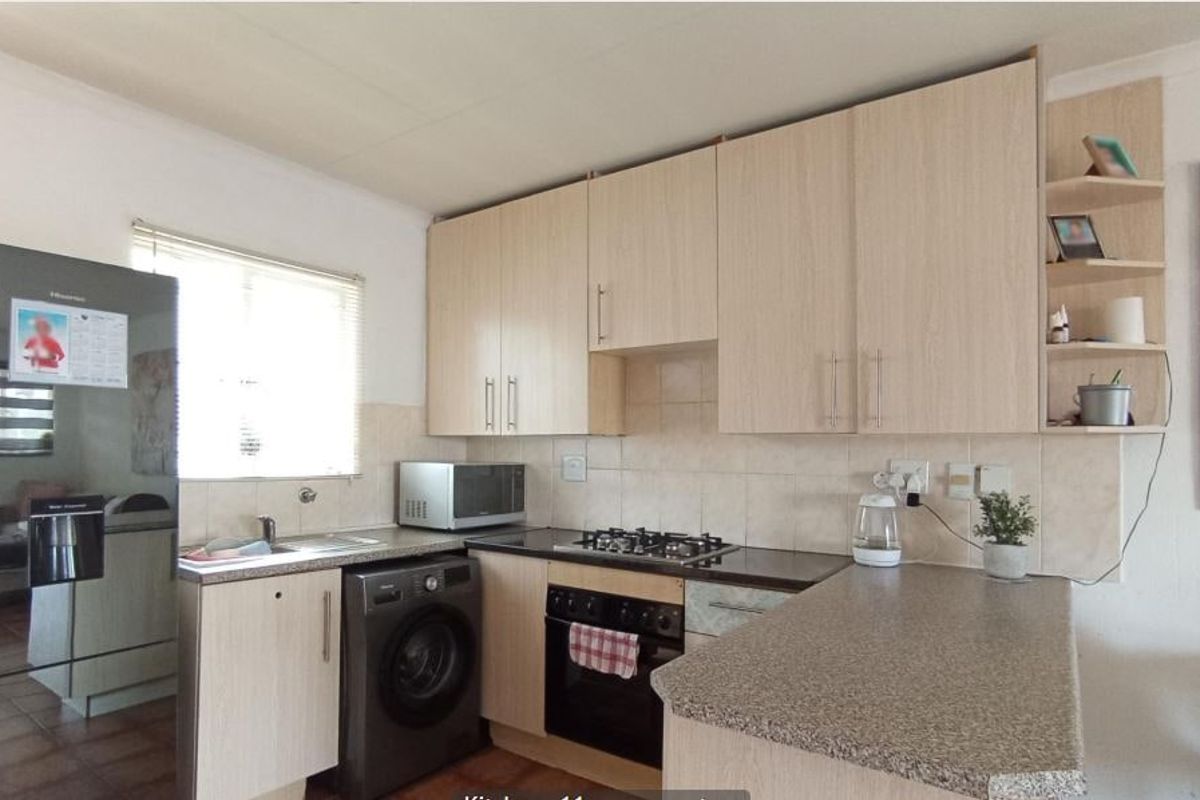 Functional kitchen featuring light wood-finish cabinetry, stone-look countertops, a built-in oven with gas hob, and a convenient breakfast bar area.
