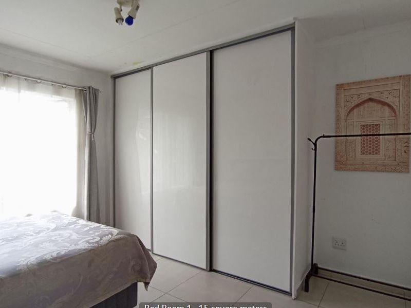 A bedroom featuring tiled flooring and a large built-in sliding door wardrobe, providing ample storage space.
