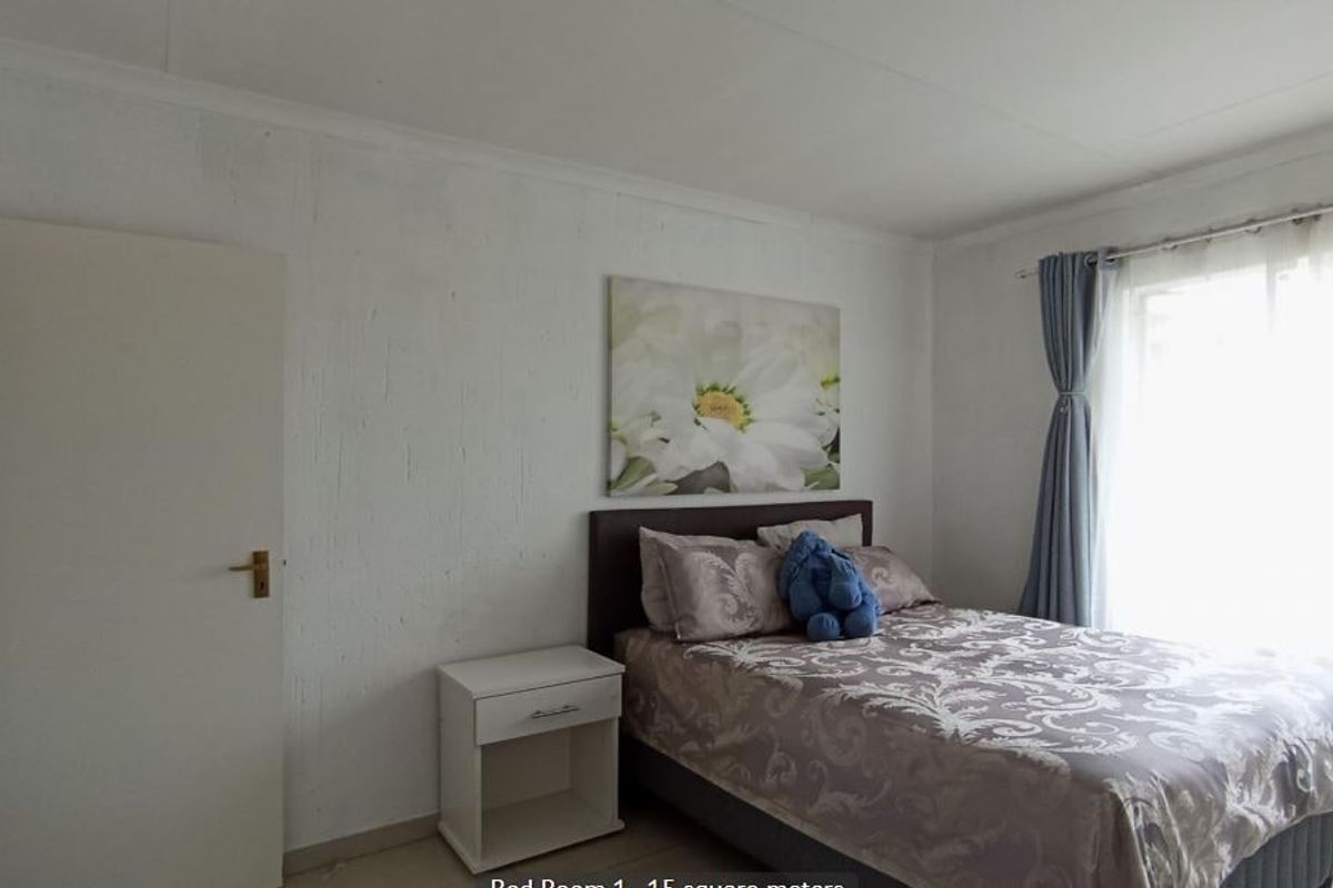A standard bedroom featuring white textured walls, cove cornicing, and natural light from a window.