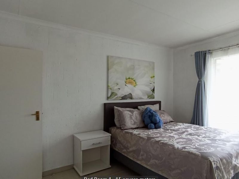 A standard bedroom featuring white textured walls, cove cornicing, and natural light from a window.