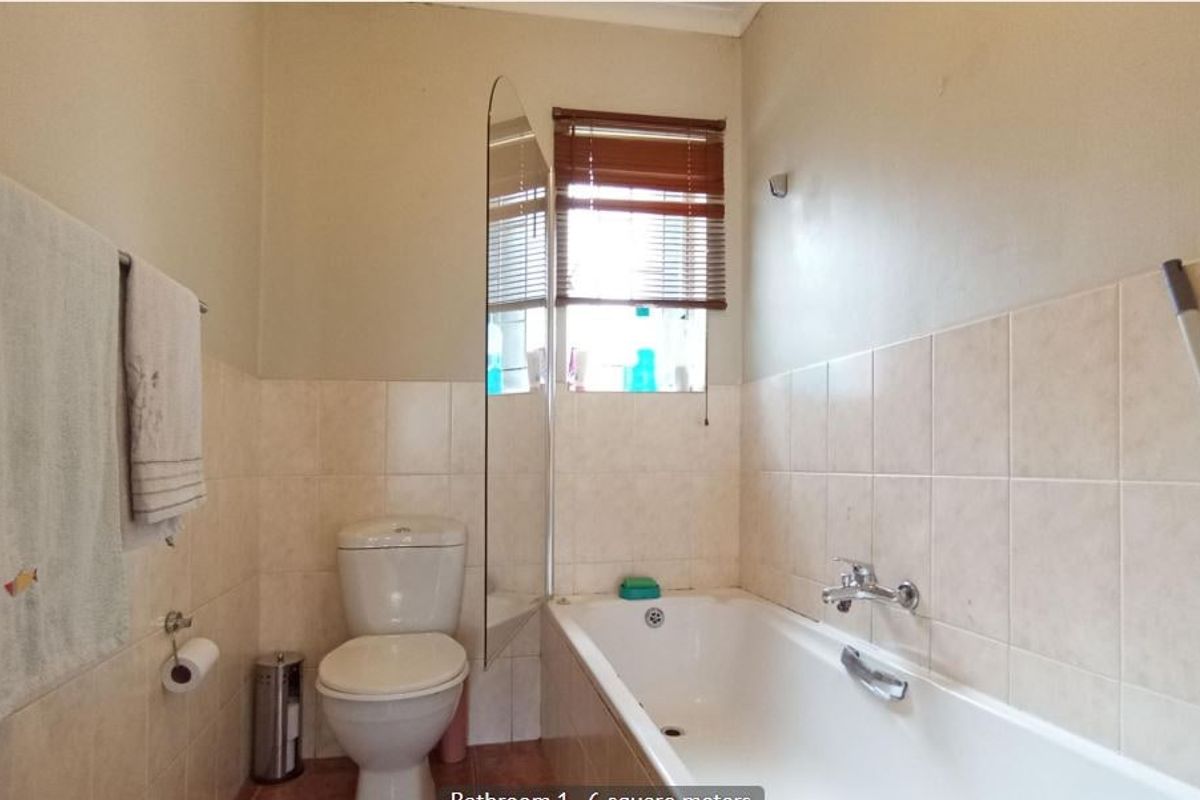 A functional bathroom featuring a standard bathtub, toilet, and partial wall tiling, providing a practical space for daily use.