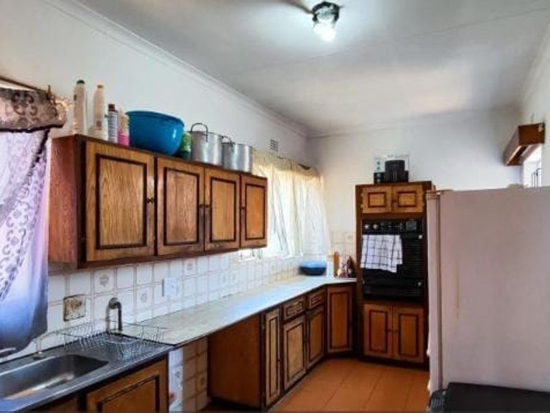 A functional kitchen featuring traditional wooden cabinetry, laminate countertops, a built-in oven, and tiled splashbacks, offering potential for a modern renovation.