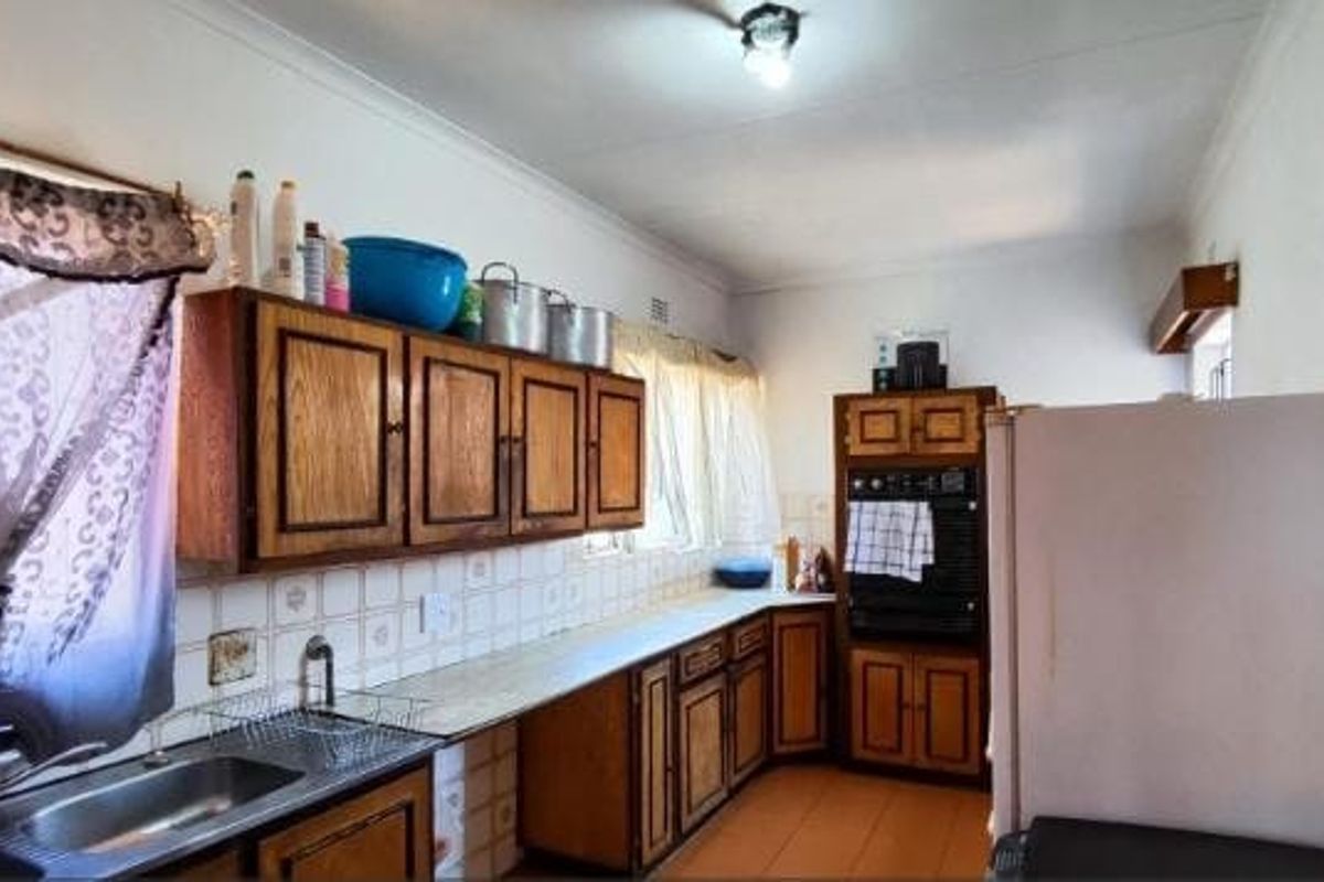 A functional kitchen featuring traditional wooden cabinetry, laminate countertops, a built-in oven, and tiled splashbacks, offering potential for a modern renovation.