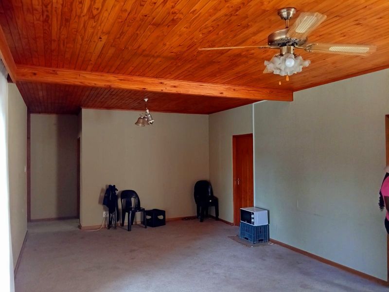 Spacious living area featuring a warm timber tongue and groove ceiling, ceiling fan, and neutral wall tones, offering a blank canvas for interior design.