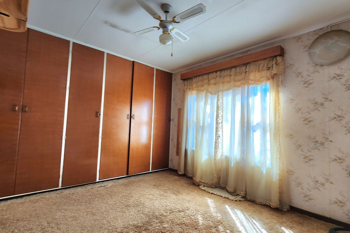 A bedroom featuring built-in wooden cupboards, a ceiling fan, and carpeted flooring, presenting an opportunity for modernization and cosmetic updates.