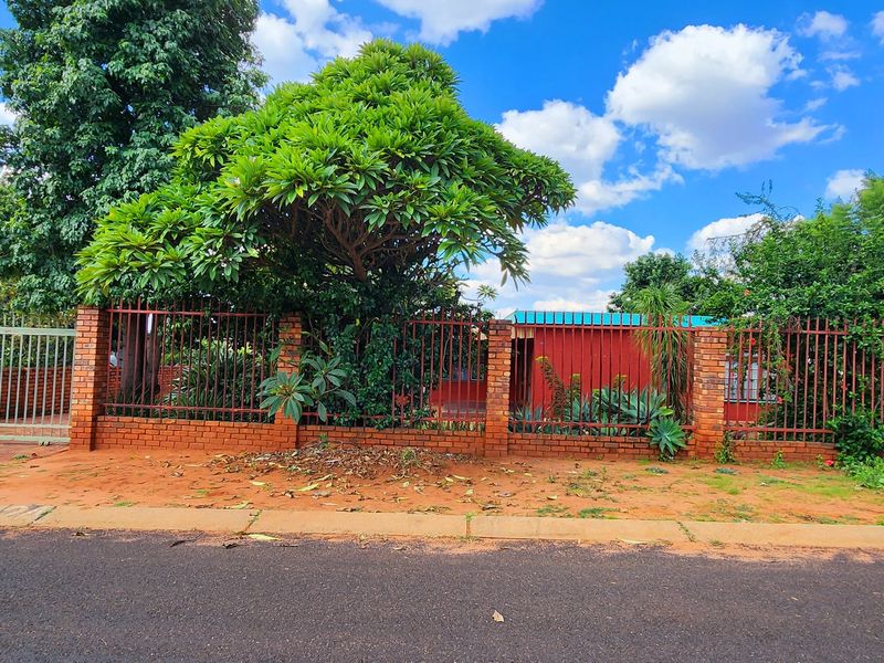 Front view of the property featuring a brick boundary wall with integrated metal security fencing and a gated driveway entrance.