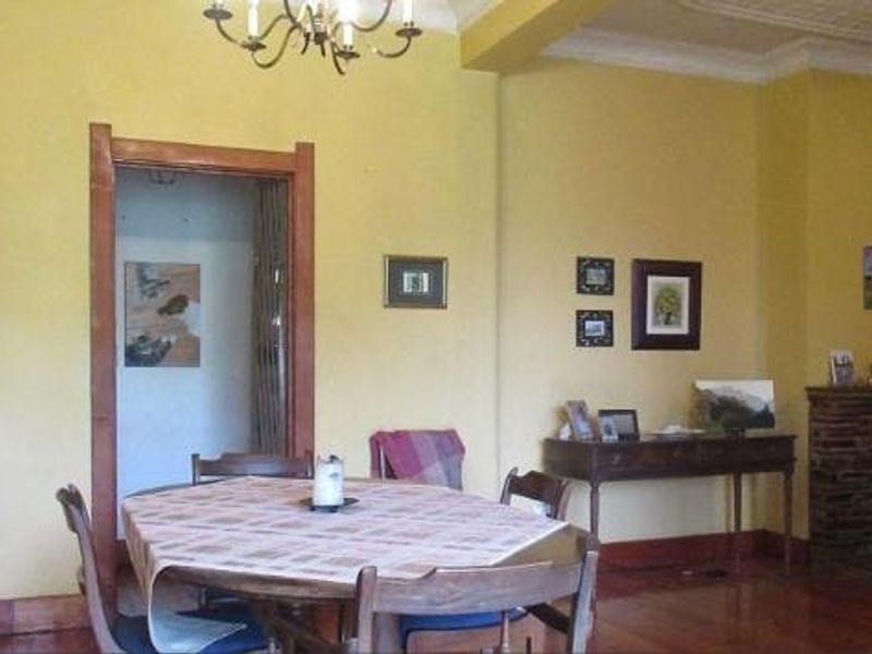 Dining room featuring hardwood flooring, decorative ceiling molding, and a stone fireplace, offering a classic and warm atmosphere.