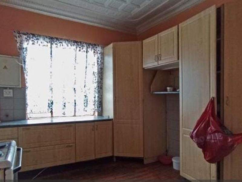 A functional kitchen featuring built-in cabinetry, a tiled backsplash, and a decorative ceiling, offering a dated but practical layout for culinary activities.