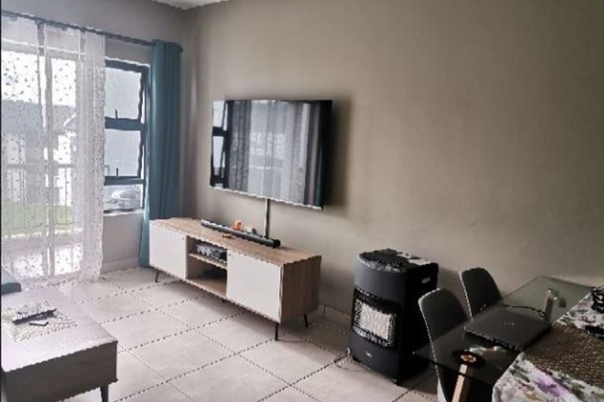 A living room area featuring tiled flooring and a sliding glass door providing access to the exterior.