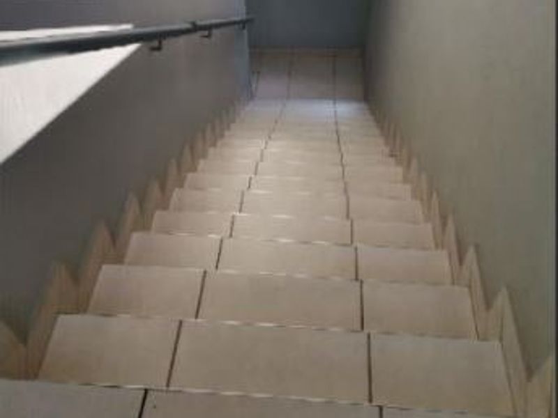 A functional tiled staircase featuring a wall-mounted metal handrail, providing access between levels within the apartment.