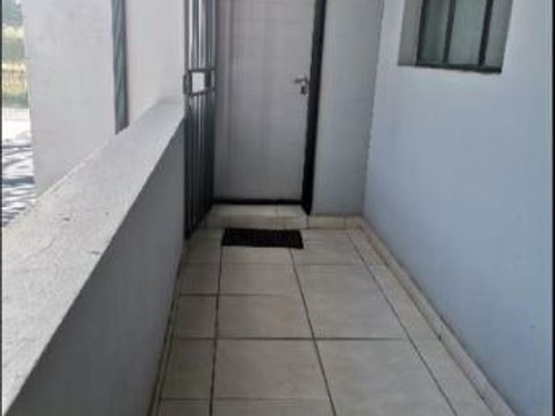 A private apartment entrance featuring tiled flooring, a security gate, and a window with a metal frame.