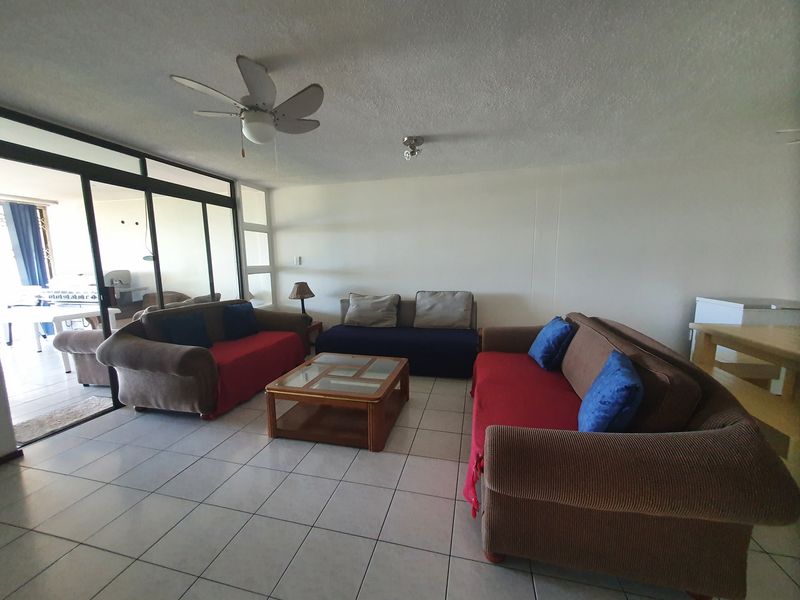 Spacious living area featuring tiled flooring, a ceiling fan, and large sliding glass doors providing access to the patio.