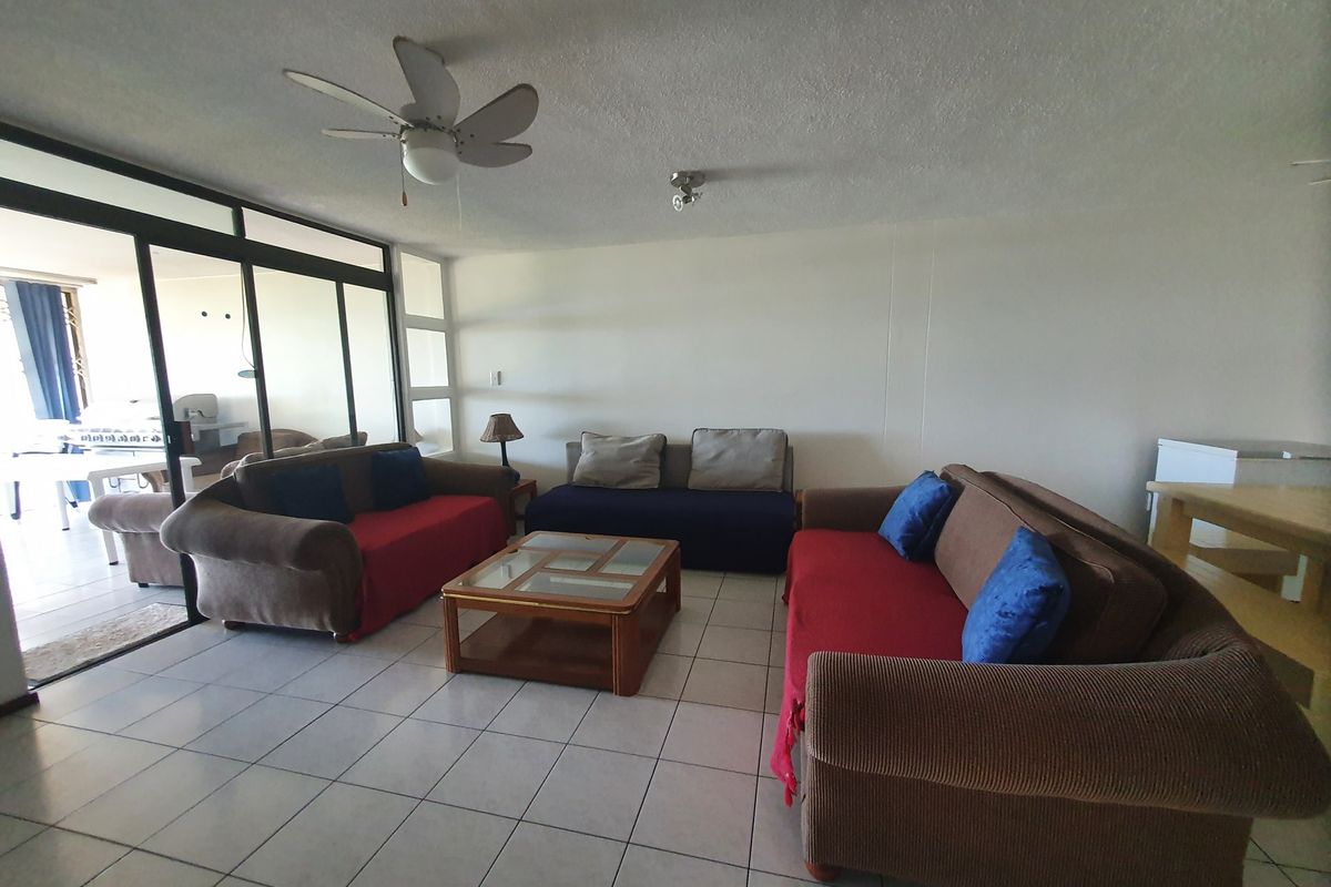 Spacious living area featuring tiled flooring, a ceiling fan, and large sliding glass doors providing access to the patio.