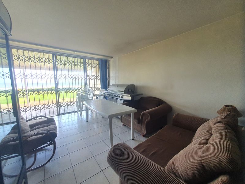 Covered patio area featuring tiled flooring, security gates, and a built-in grill, offering direct access to the outdoor space.