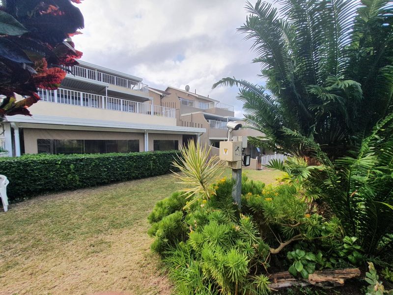 Rear view of the apartment complex featuring multi-level balconies, well-maintained garden areas, and integrated security surveillance infrastructure.