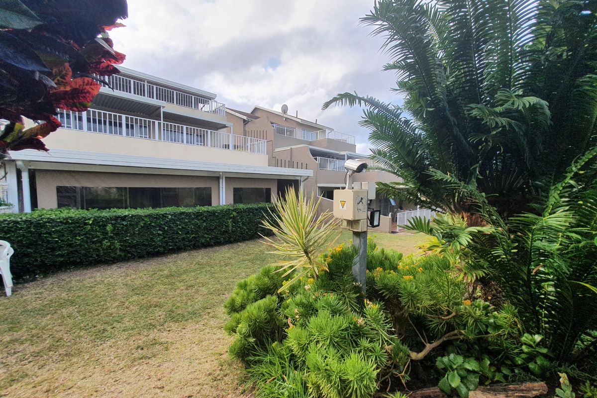 Rear view of the apartment complex featuring multi-level balconies, well-maintained garden areas, and integrated security surveillance infrastructure.