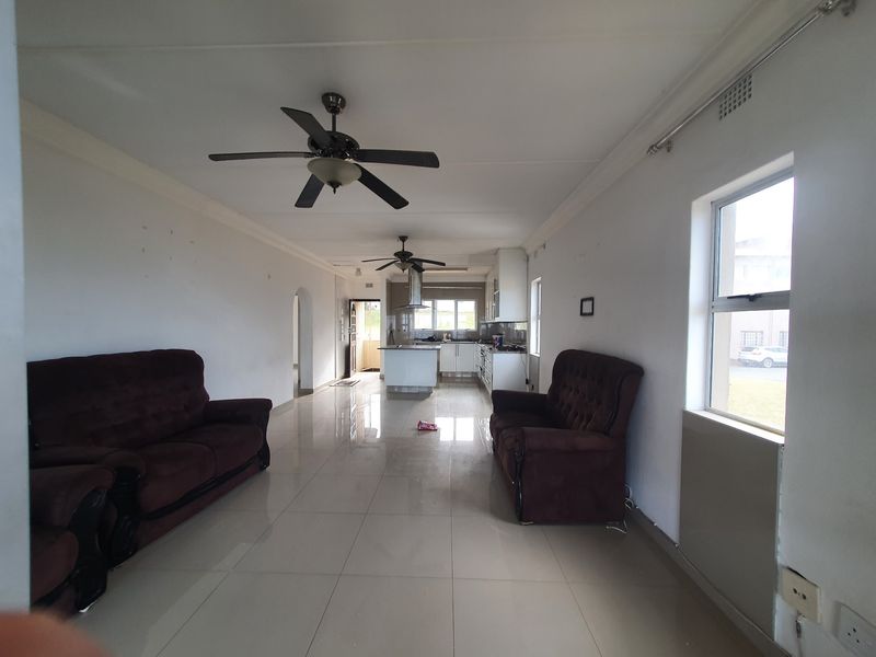 Open-plan living and kitchen area featuring tiled floors, ceiling fans, and a functional kitchen layout with built-in cabinetry and appliances.