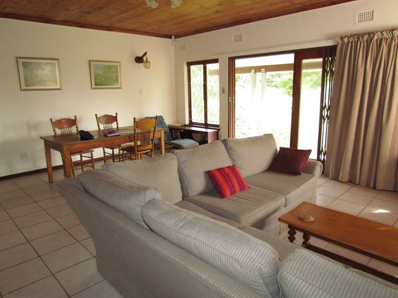 Open plan living and dining area featuring ceramic floor tiles, a timber ceiling, and sliding glass doors providing access to the outdoor space.