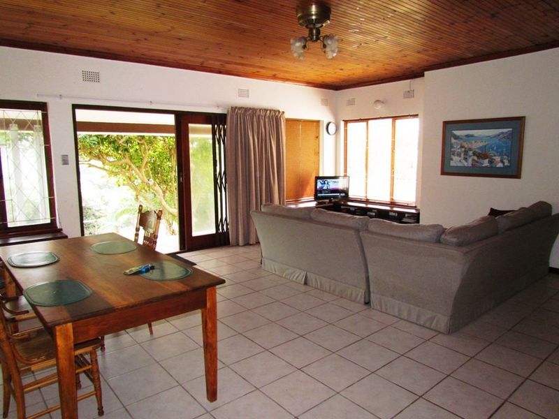 Open plan living and dining area featuring ceramic floor tiles, a timber tongue and groove ceiling, and direct access to the outdoor patio.