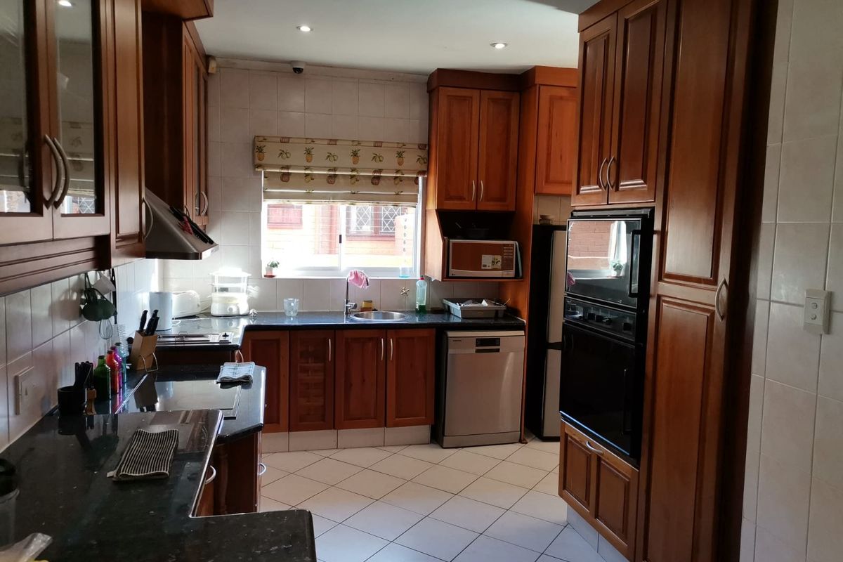 A functional kitchen featuring warm-toned wooden cabinetry, granite countertops, built-in oven, and tiled flooring, offering a classic and practical layout.