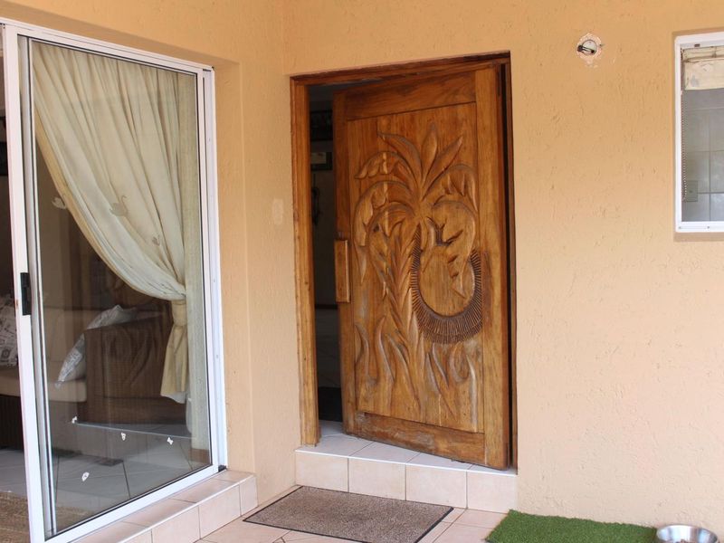 Covered patio area featuring a decorative carved wooden entrance door and a sliding glass door leading into the home.