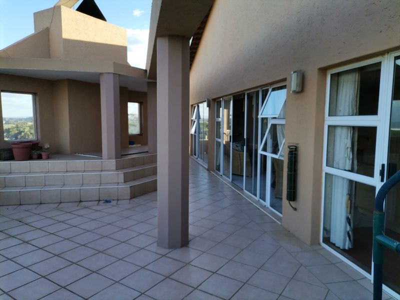 Spacious covered patio area featuring tiled flooring, structural columns, and large sliding glass doors providing access to the interior living spaces.