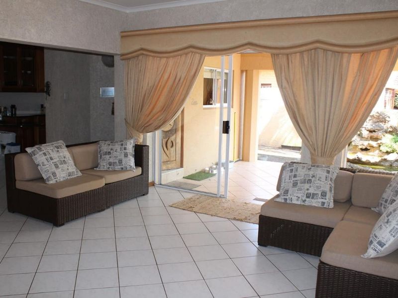 A living room featuring tiled flooring and a sliding glass door providing access to an outdoor patio area, with an adjacent kitchen space.