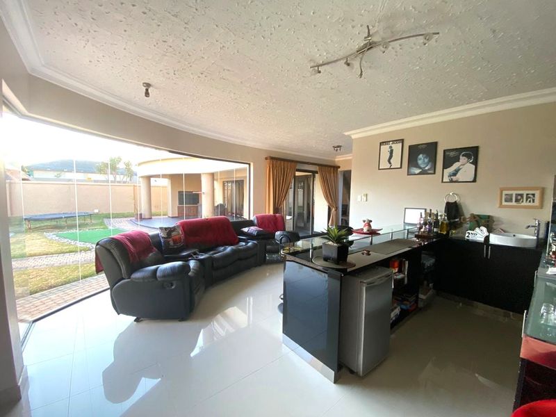 Spacious open-plan living area featuring a built-in bar with sink, large glass sliding doors, and seamless access to the outdoor patio and garden.
