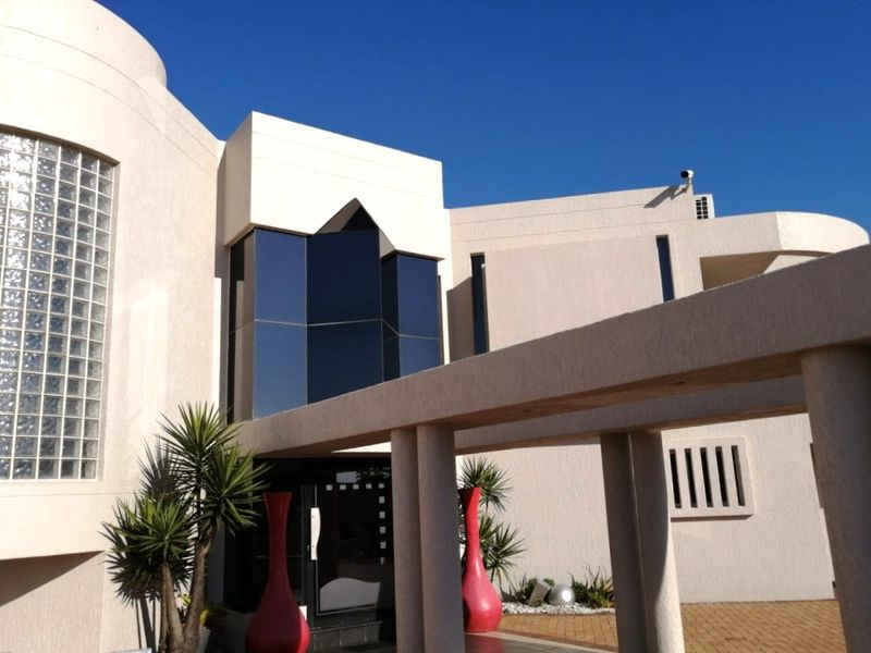 Modern architectural front facade featuring a covered walkway, textured exterior walls, and a distinctive glass block window design.