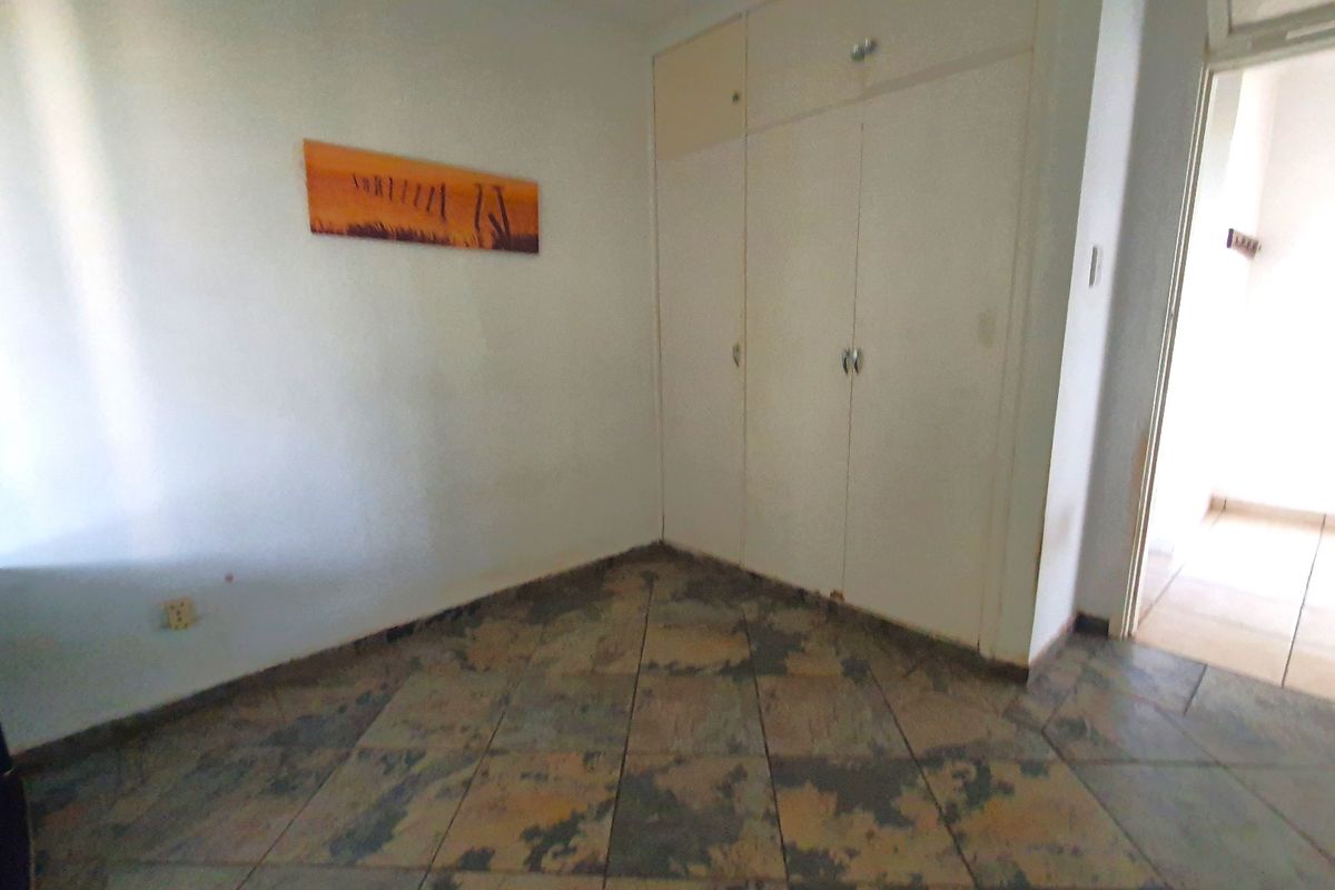 A bedroom featuring built-in cupboards and tiled flooring, presenting a blank canvas ready for updates and personal styling.