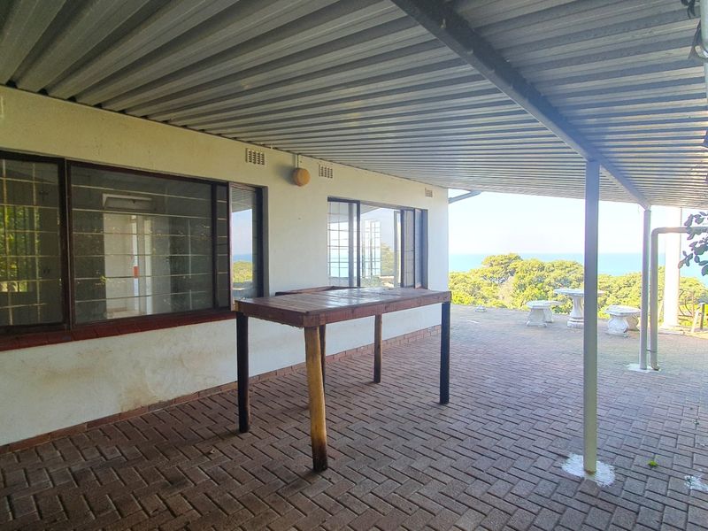 A covered outdoor patio area featuring brick paving, metal roofing, and ocean views, providing a functional space for outdoor relaxation.