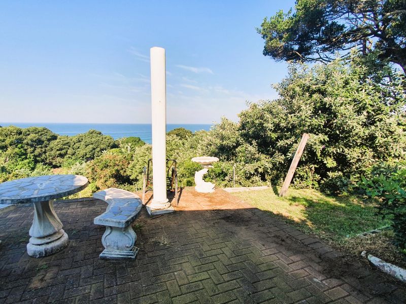Outdoor paved patio area featuring a structural column and scenic ocean views, offering potential for a tranquil garden entertainment space.